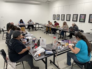 several people working on art projects at tables arranged in a square
